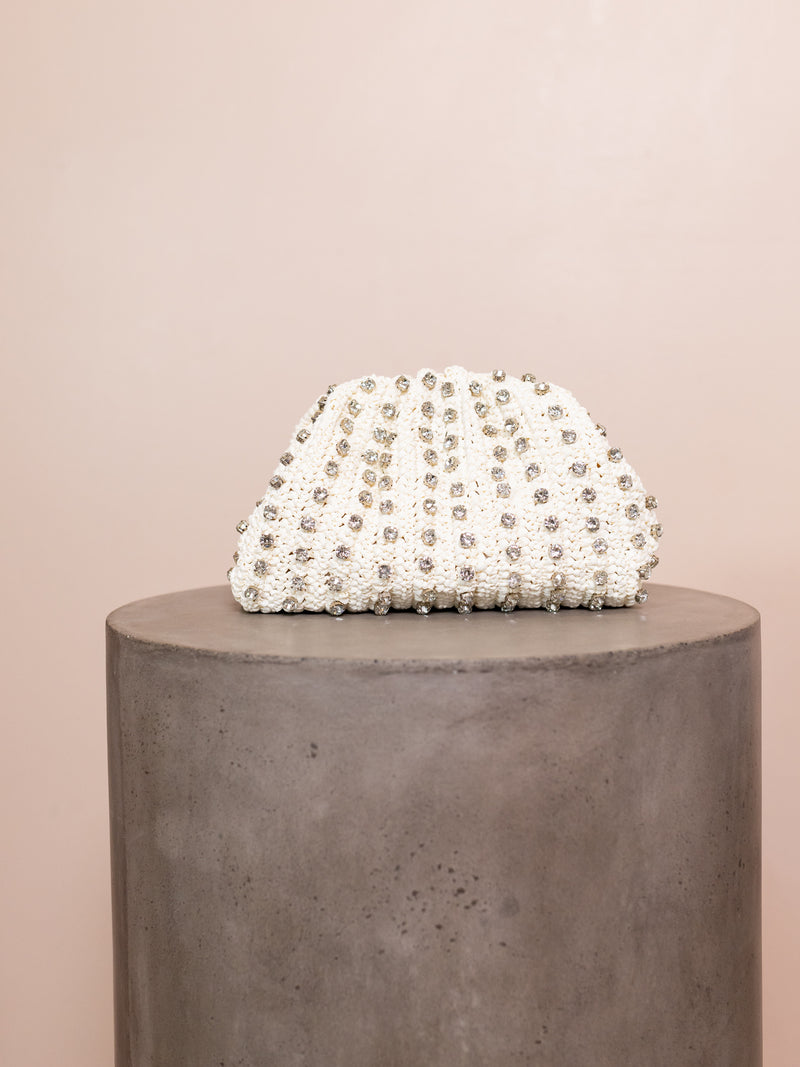 White woven clutch studded with crystals against pink background.