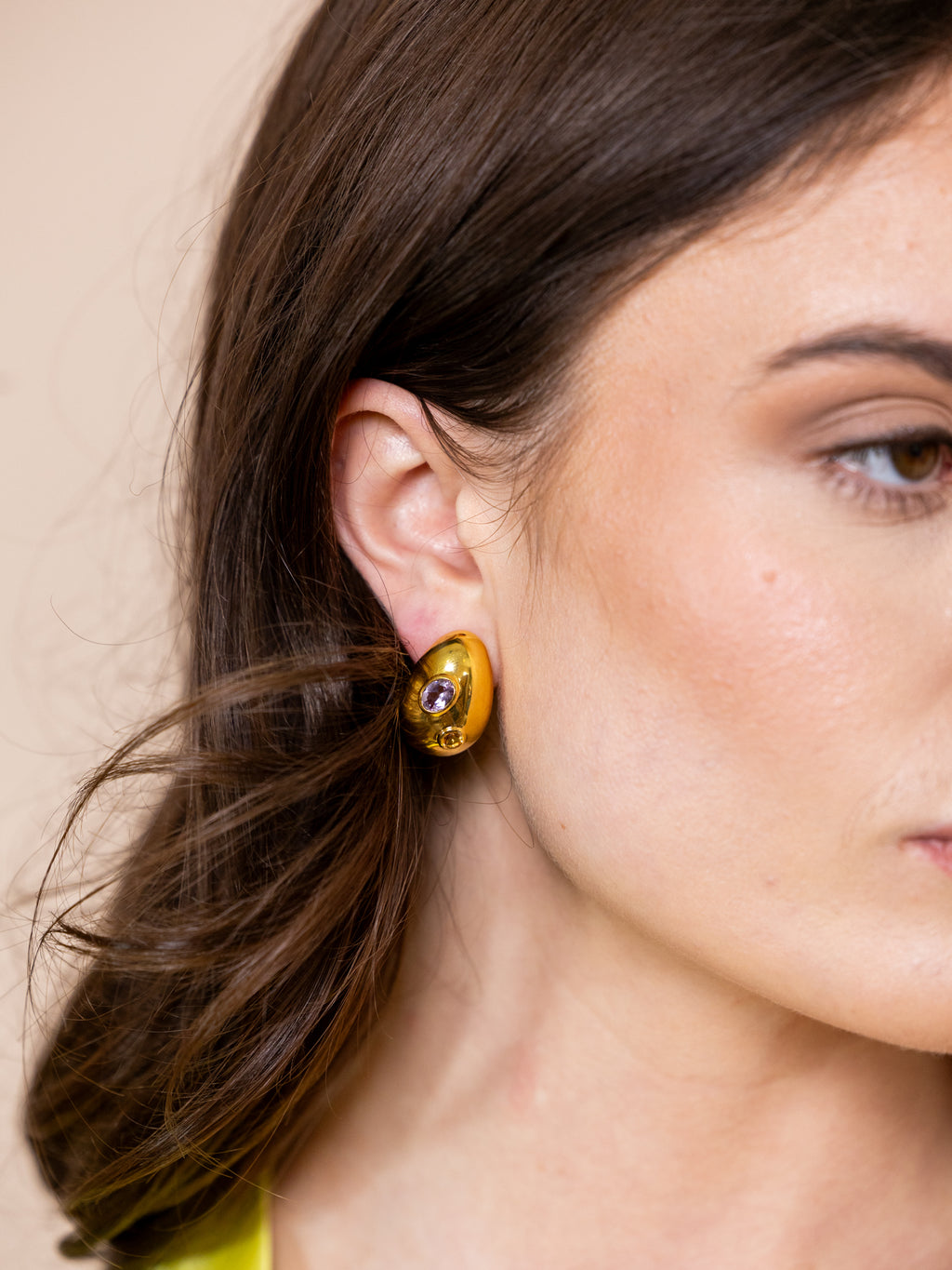 Woman wearing gold earrings with inlaid jewels.