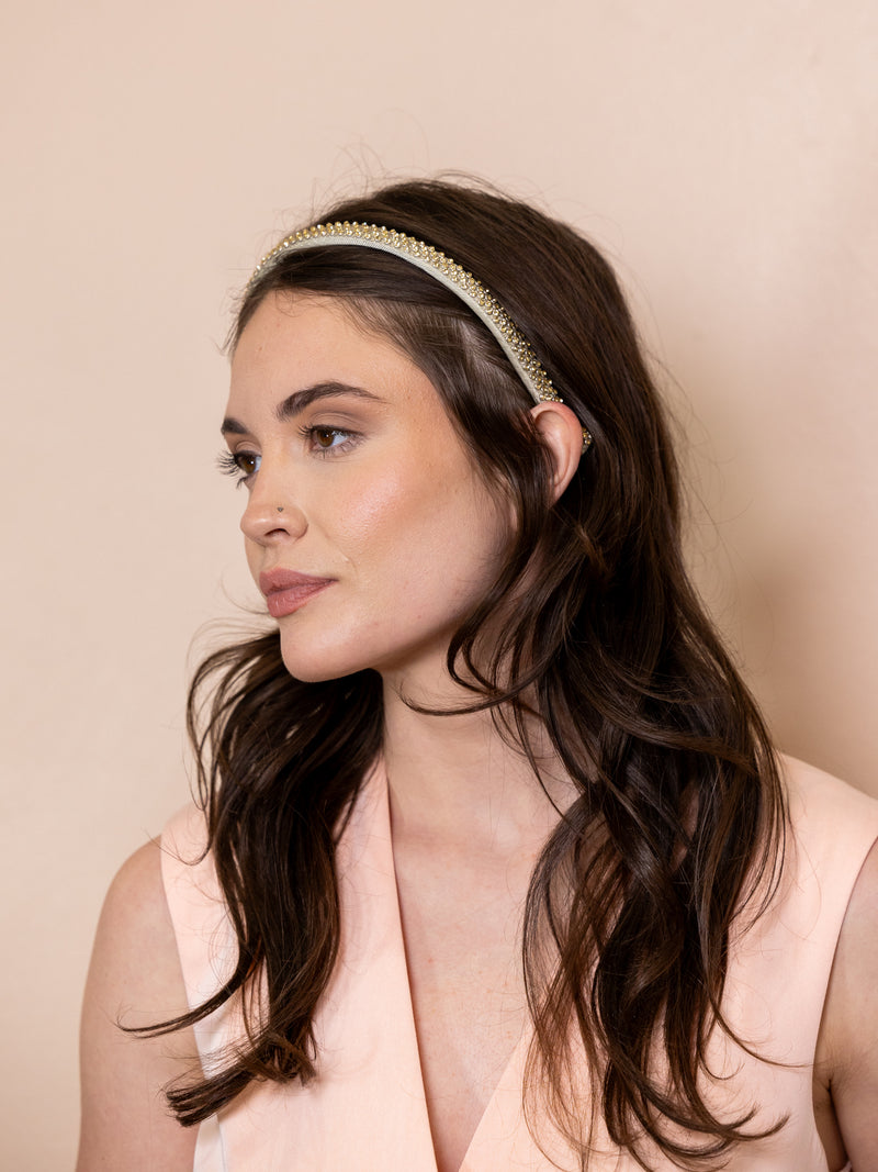 Woman wearing crystal studded headband against pink background