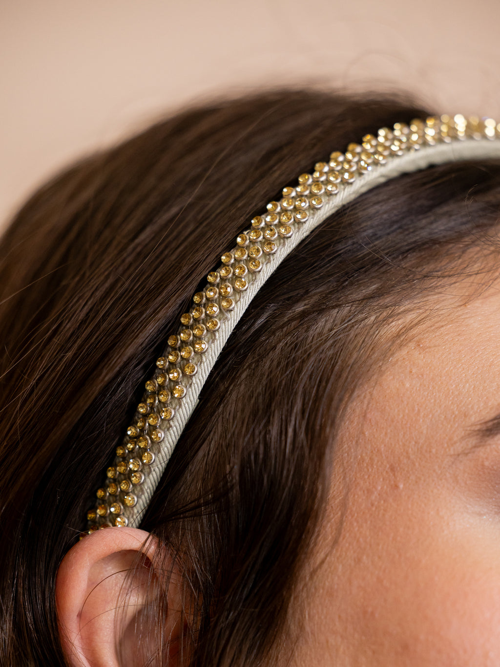 Woman wearing crystal studded headband against pink background