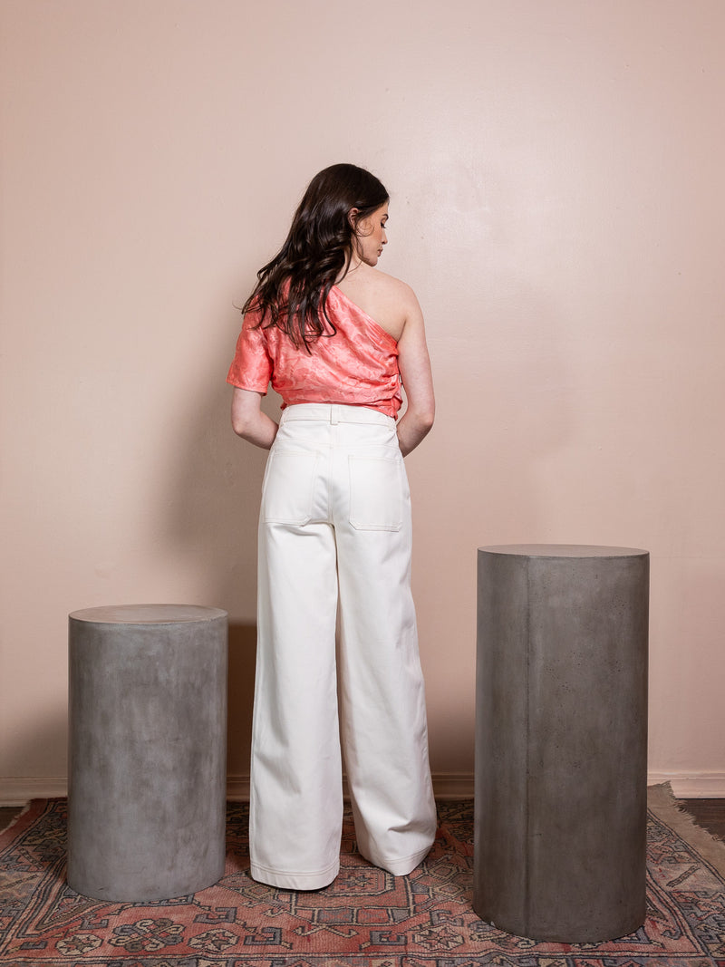 Woman in pink top and white pants against pink background