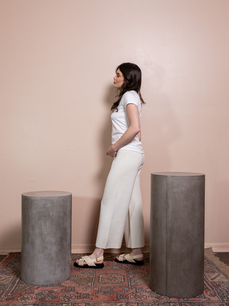 Woman in white t-shirt and white pants against pink background