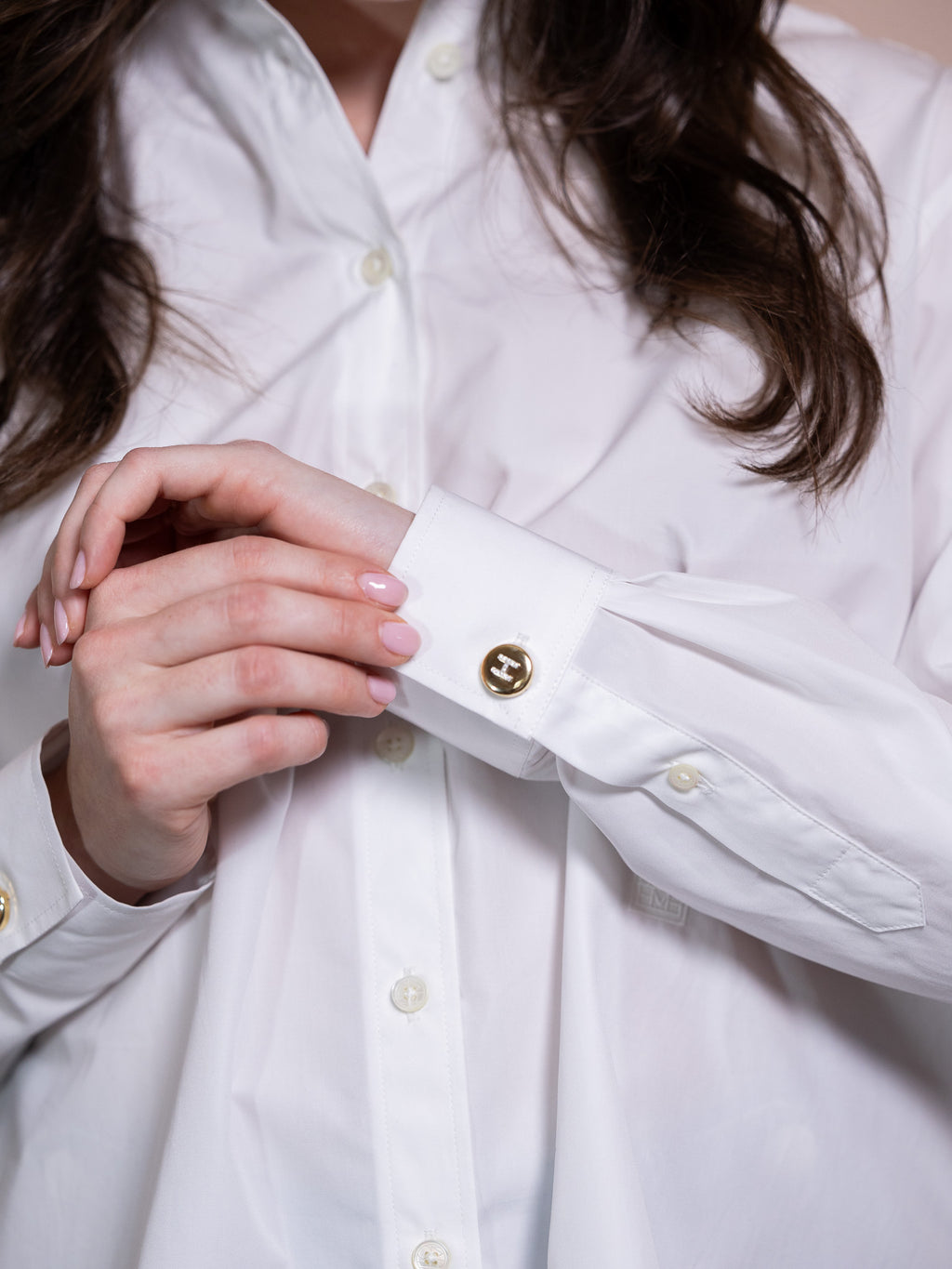 Gold button cover with diamond H on white shirt