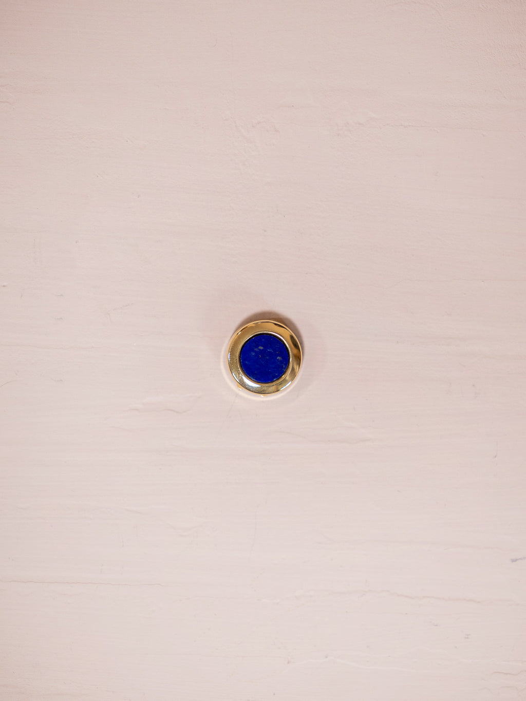 Lapus lazuli and gold button cover on pink background.