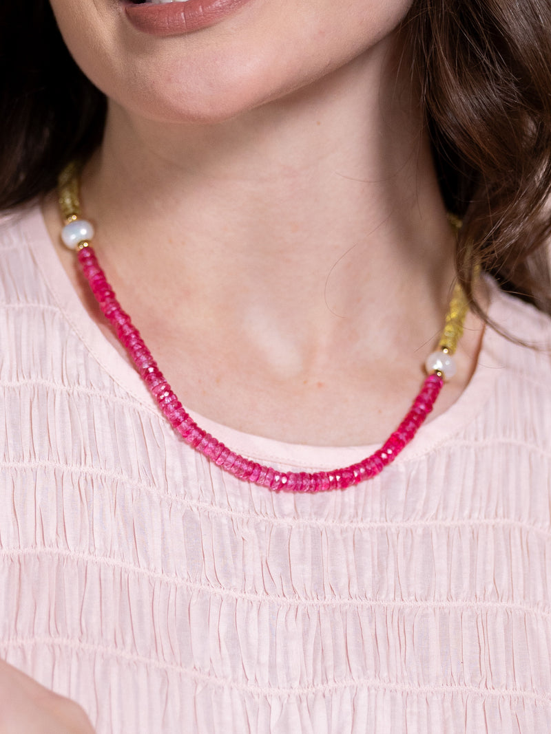 Woman wearing necklace with pearls and yellow and pink beads.