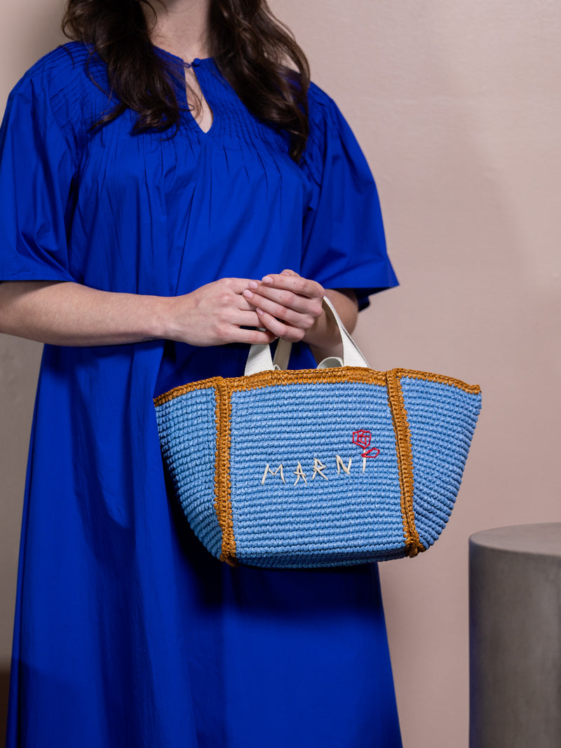 Woman in blue dress holding blue bag