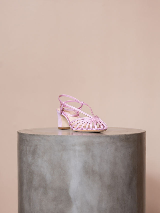 Pink heel on pedestal against pink background
