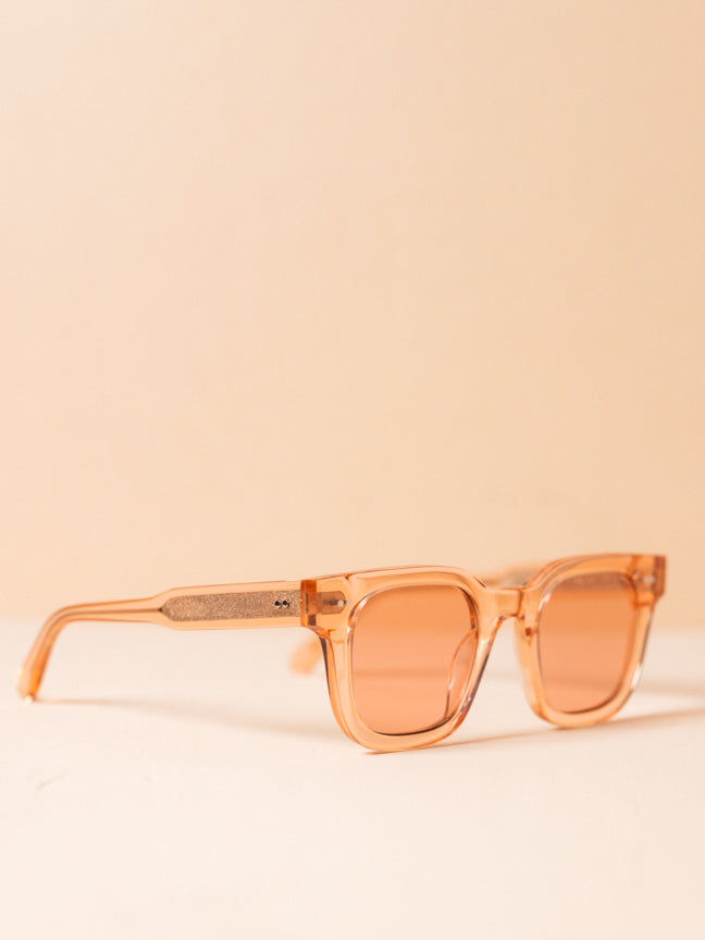 CHIMI-04 PINK. Square framed sunglasses with clear, pink toned frames and lenses. Two silver rivets at the sides of the frames and the fronts of the legs..