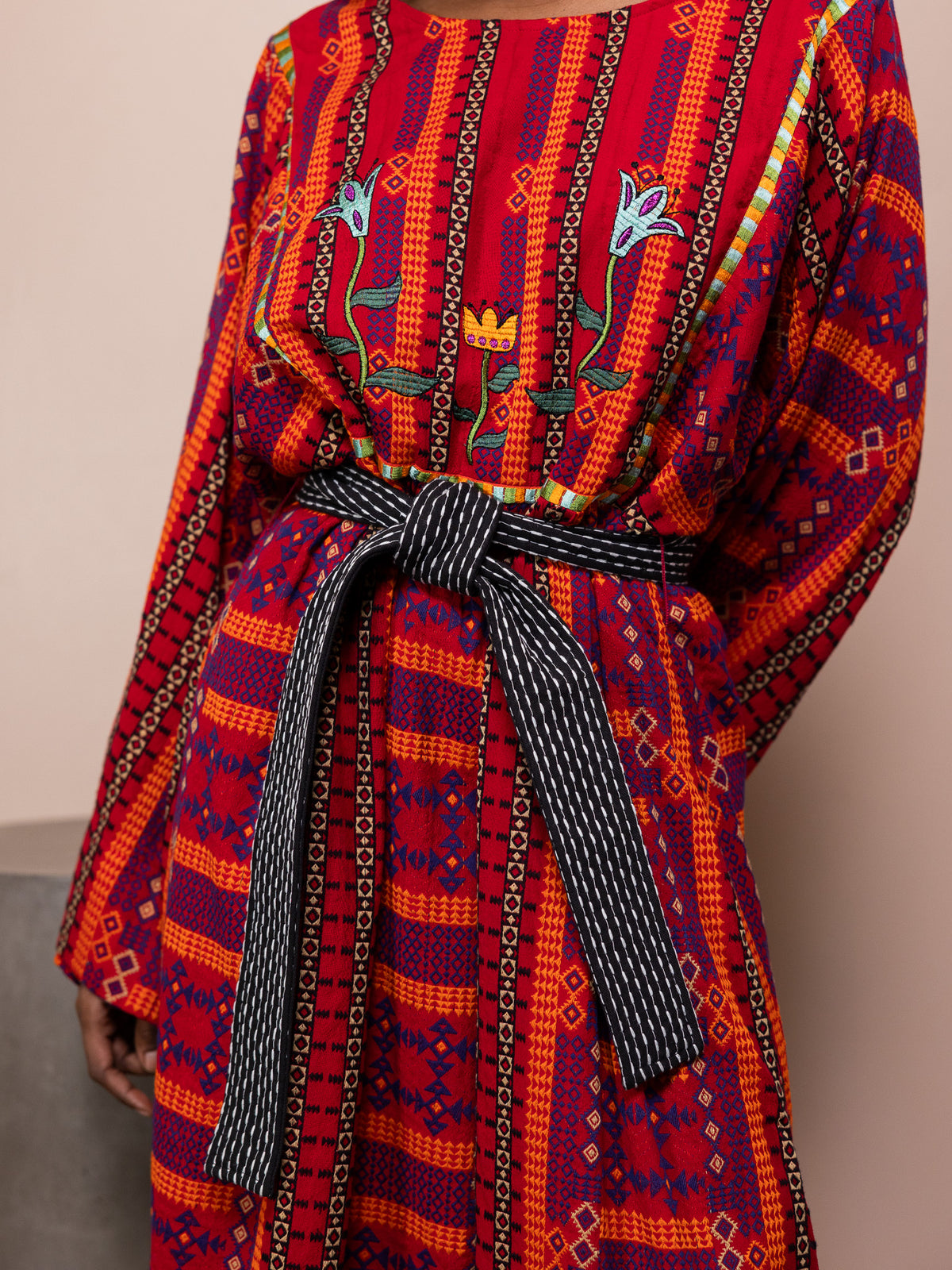 Woman wearing patterned red dress against pink background.