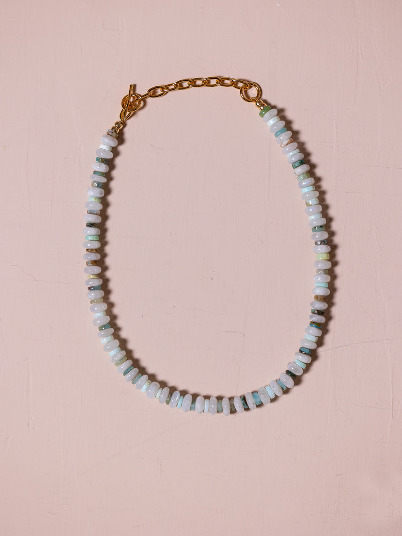 Necklace with blue beads against pink background.