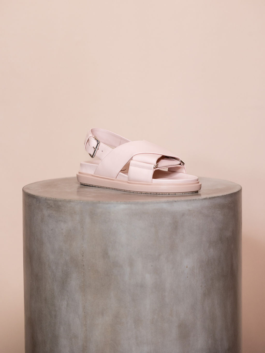 Pink sandals on podium against pink background