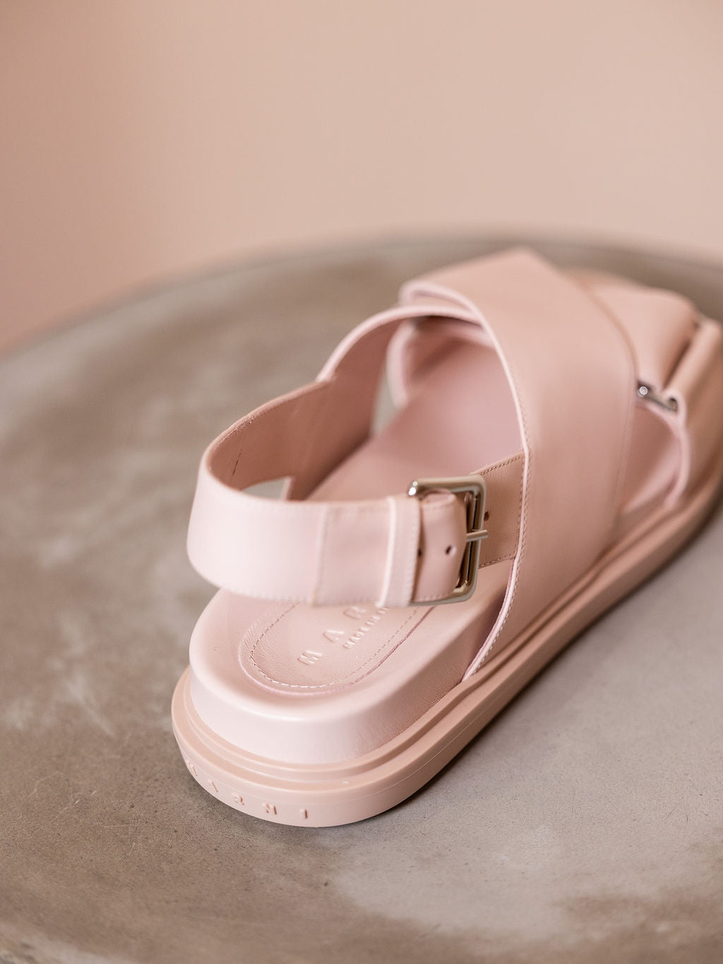 Pink sandals on podium against pink background