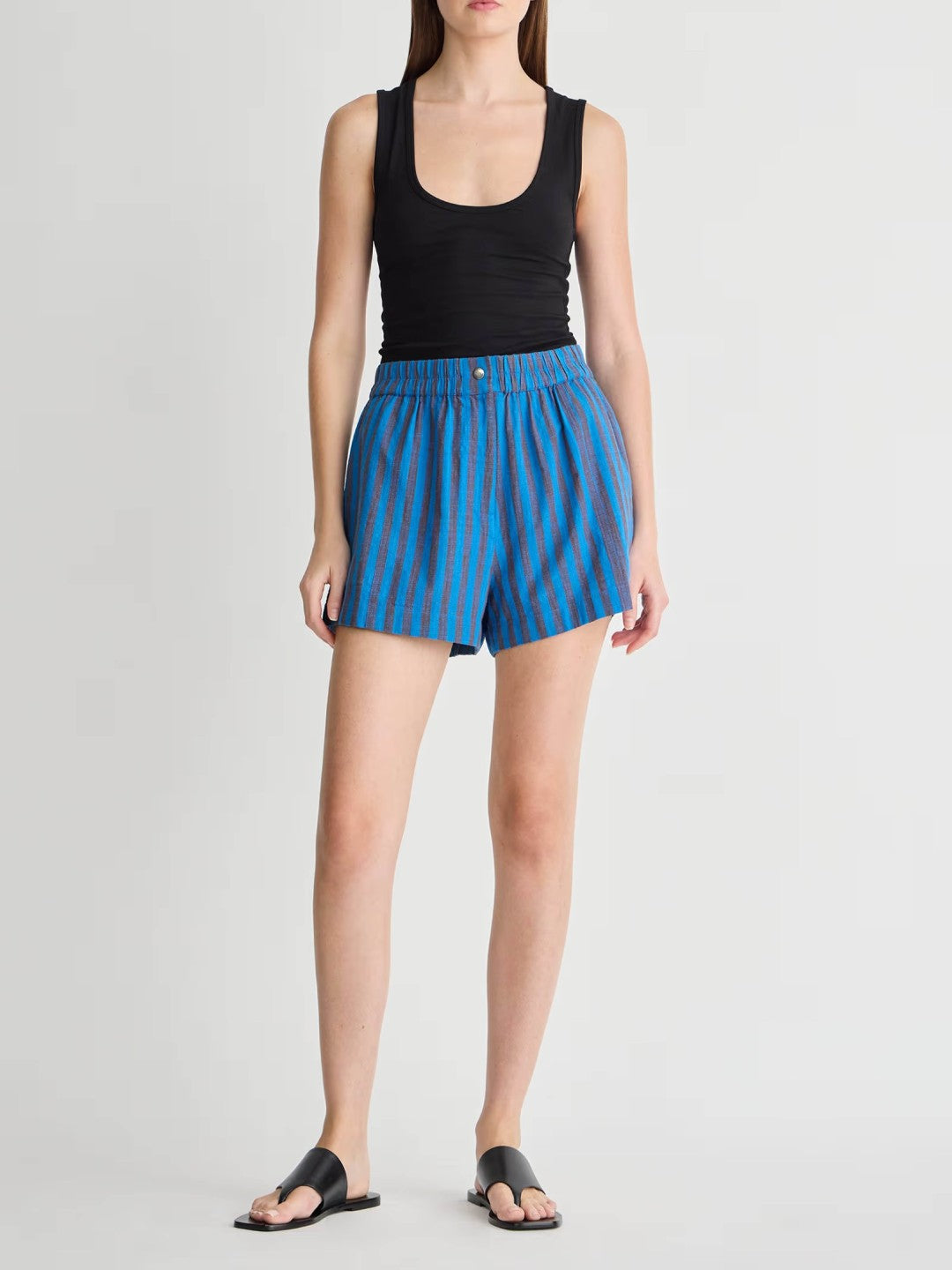 Woman wearing blue striped shorts and a black tank top on a white background