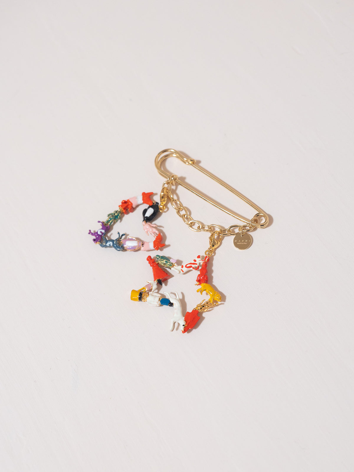 Gold brooch with colorful charms on a light gray background
