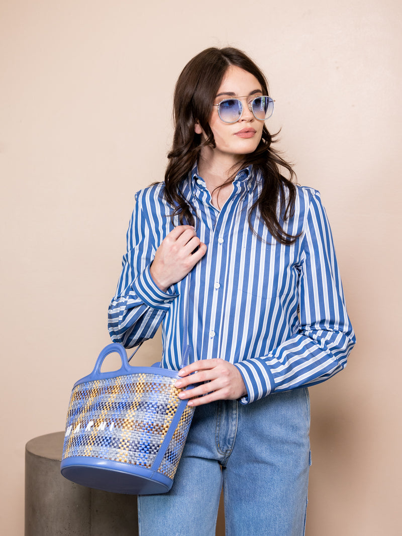 Woman in striped shirt and blue jeans wearing blue wireframe sunglasses