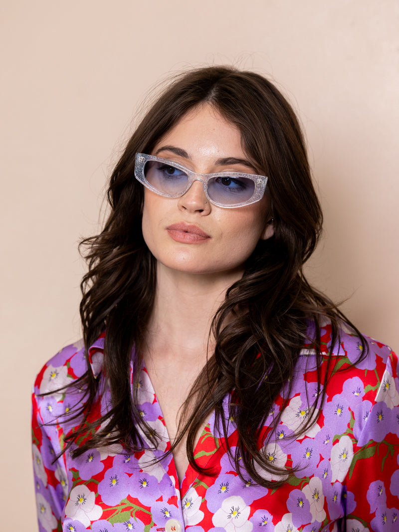 Woman wearing clear sunglasses with blue frames.