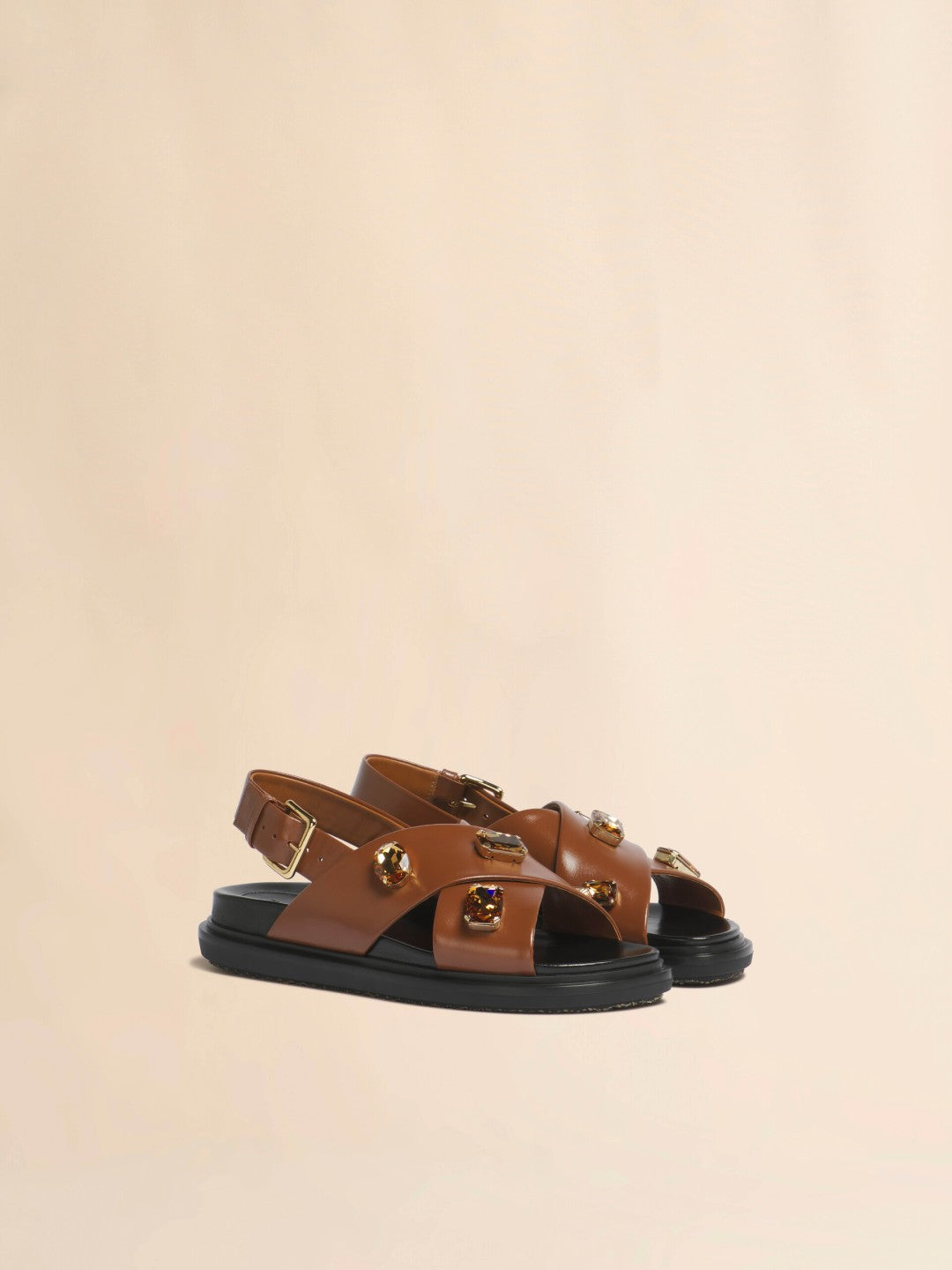 Pair of brown sandals with black soles on a beige background