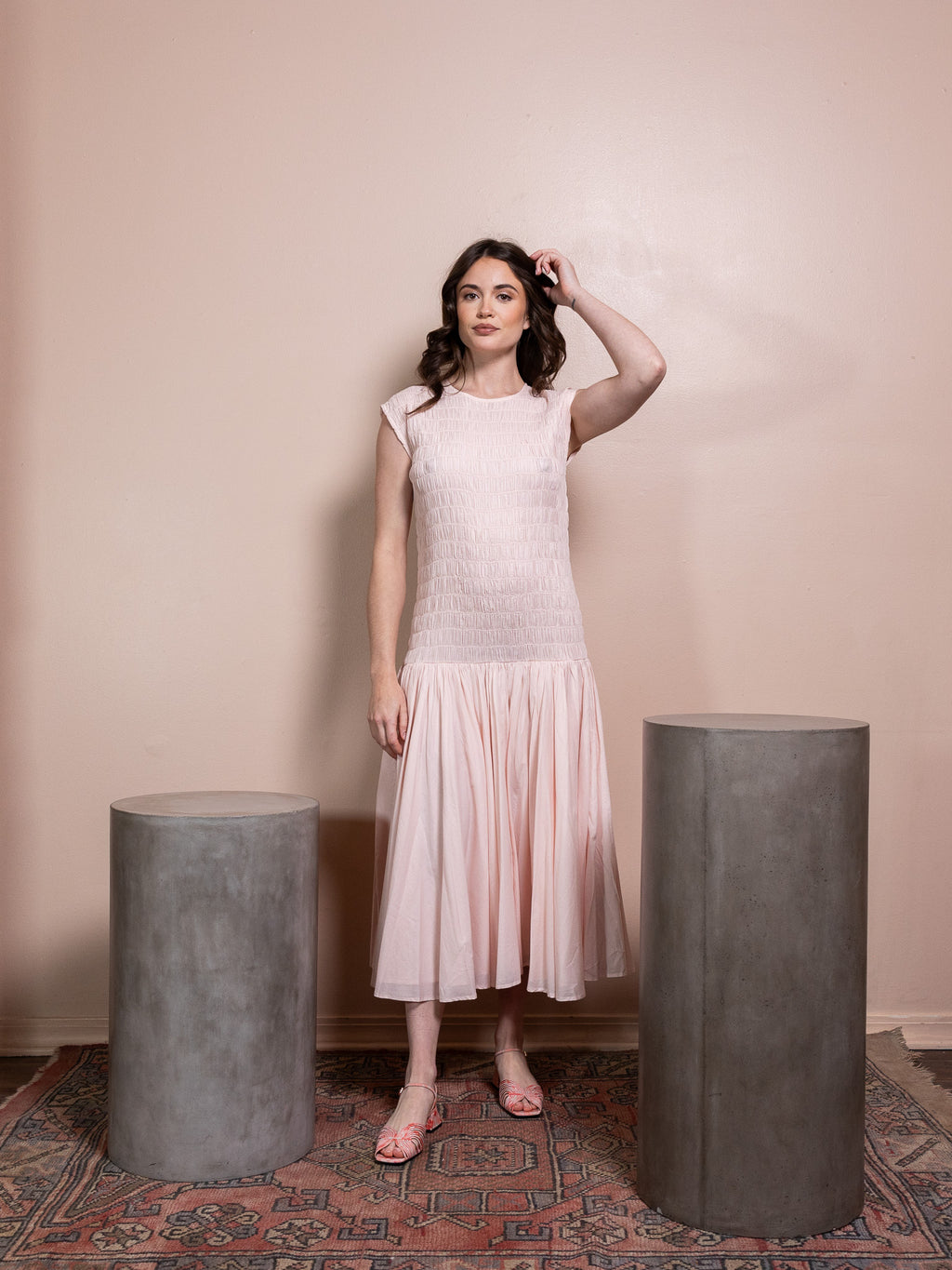 Woman in pink ruched dress against pink background