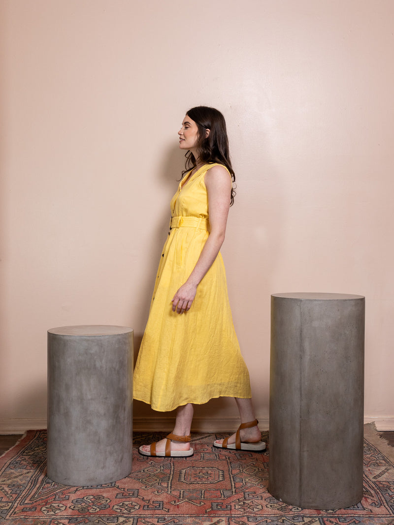 Woman in button down yellow dress against pink background