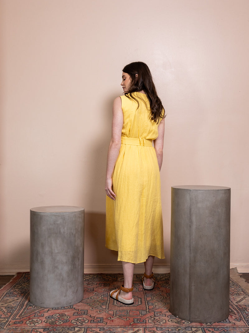Woman in button down yellow dress against pink background