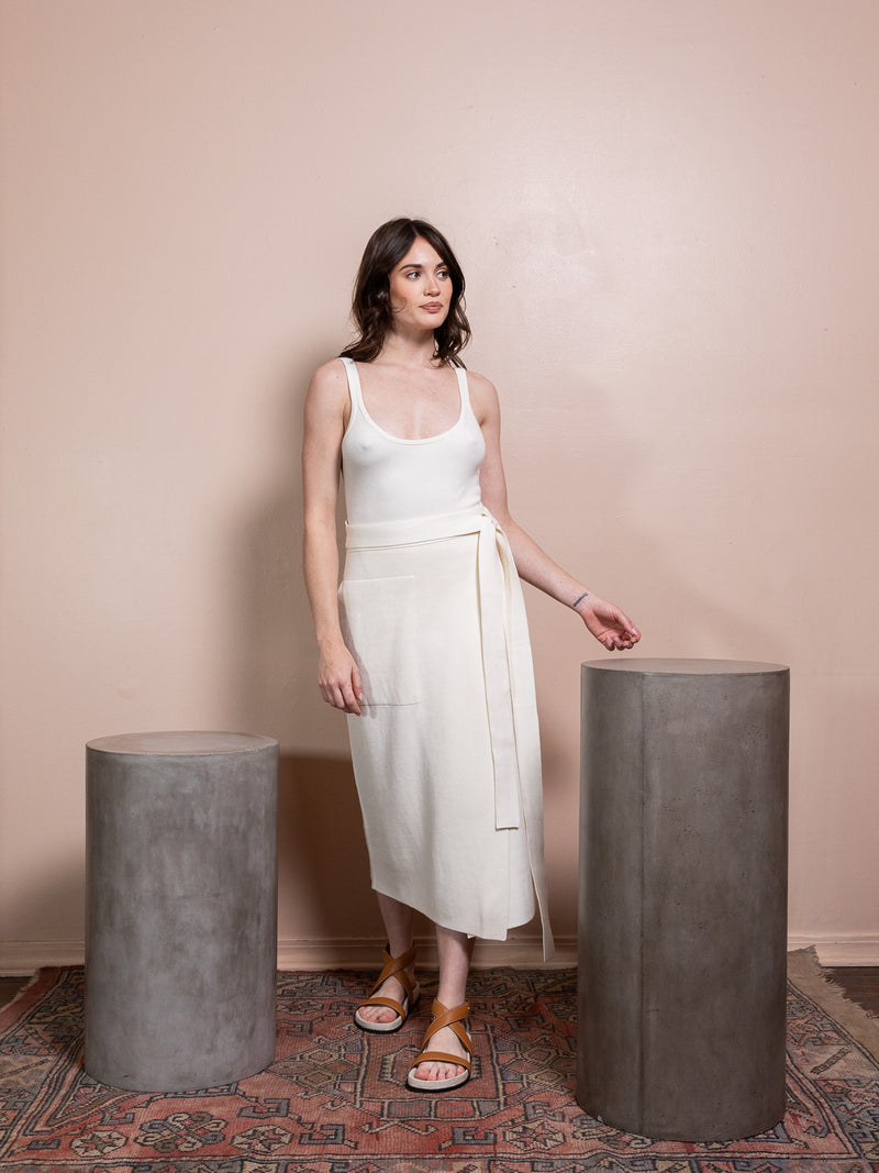 Woman in white tank top and white skirt against pink background