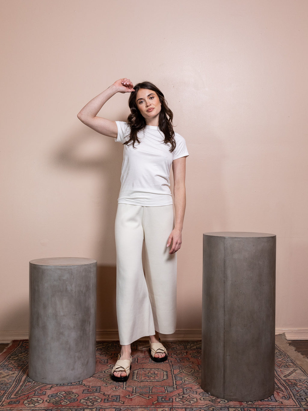 Woman in white t-shirt and white pants against pink background