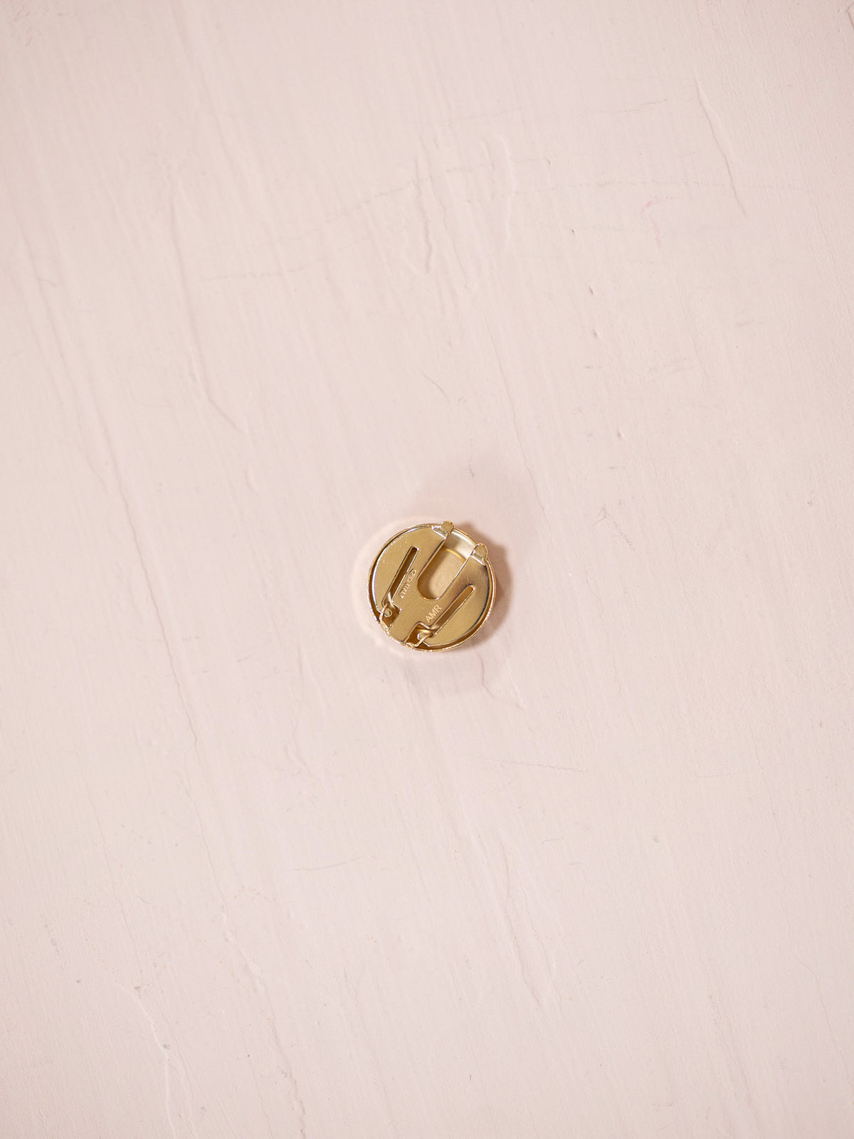 Back of button cover on pink background.