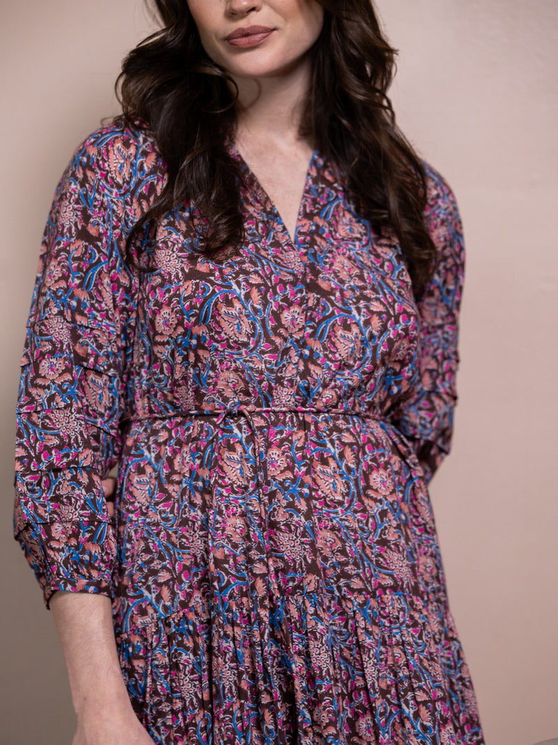 Woman in purple floral dress against pink background