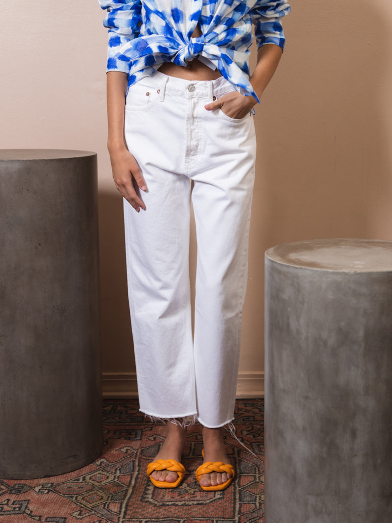 Woman wearing Agolde white jeans. The jeans have a loose fit and a raw hem. Agolde 90s crop pant. Style Number: A173-1183