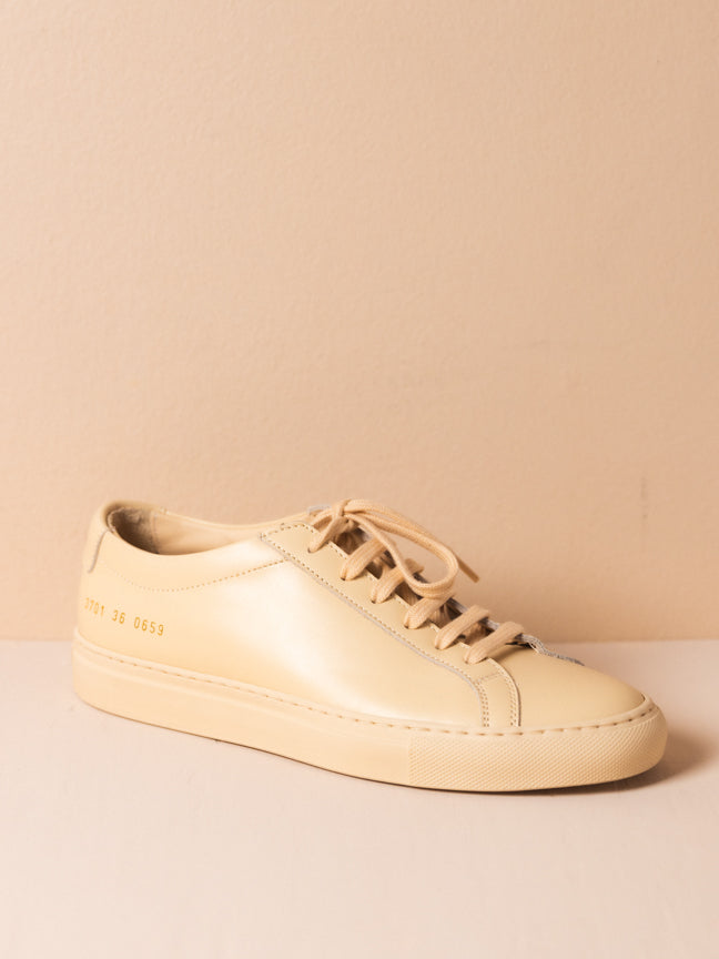 Common Projects tan sneaker with tan laces and gold embossed numbers on the side. Achilles Low Sneaker in Nude. Style Number: 3701