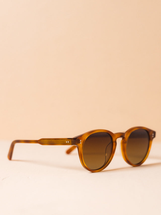 Chimi-03 Havana Core. Side view of round. light brown sunglasses with light brown frames and two silver rivets at the front and at the front of the legs.