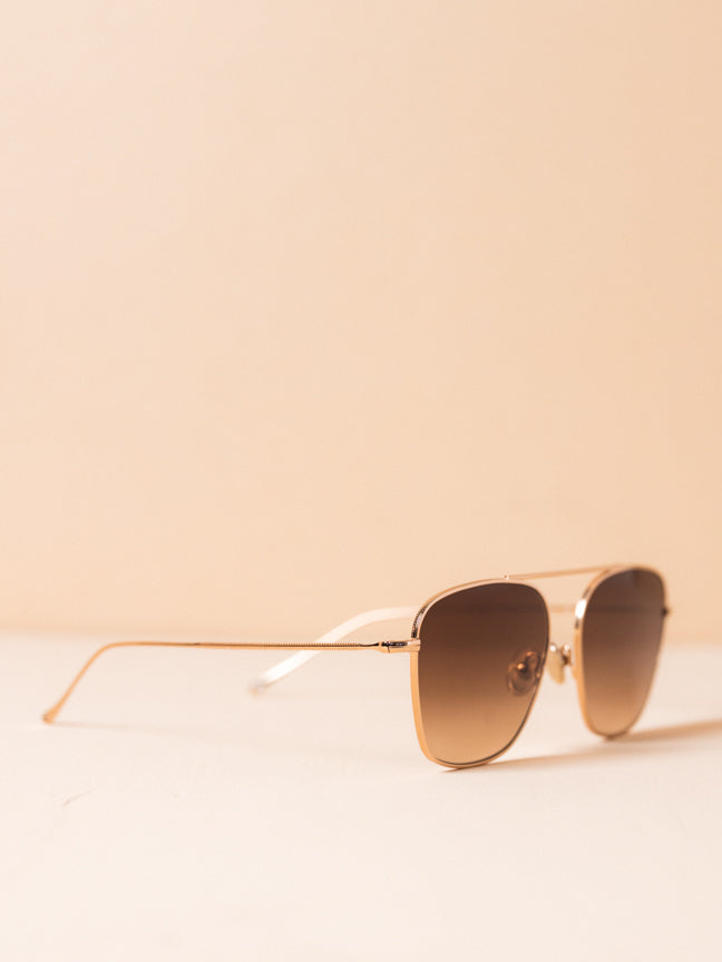 Side view of Illesteva wire framed sunglasses with a single bridge at the the brown and nose pads. The frames are a subtle rose gold and the lenses are a light brown ombre. Illesteva Samos sunglasses in rose gold. Style Number: SMO3BRFG